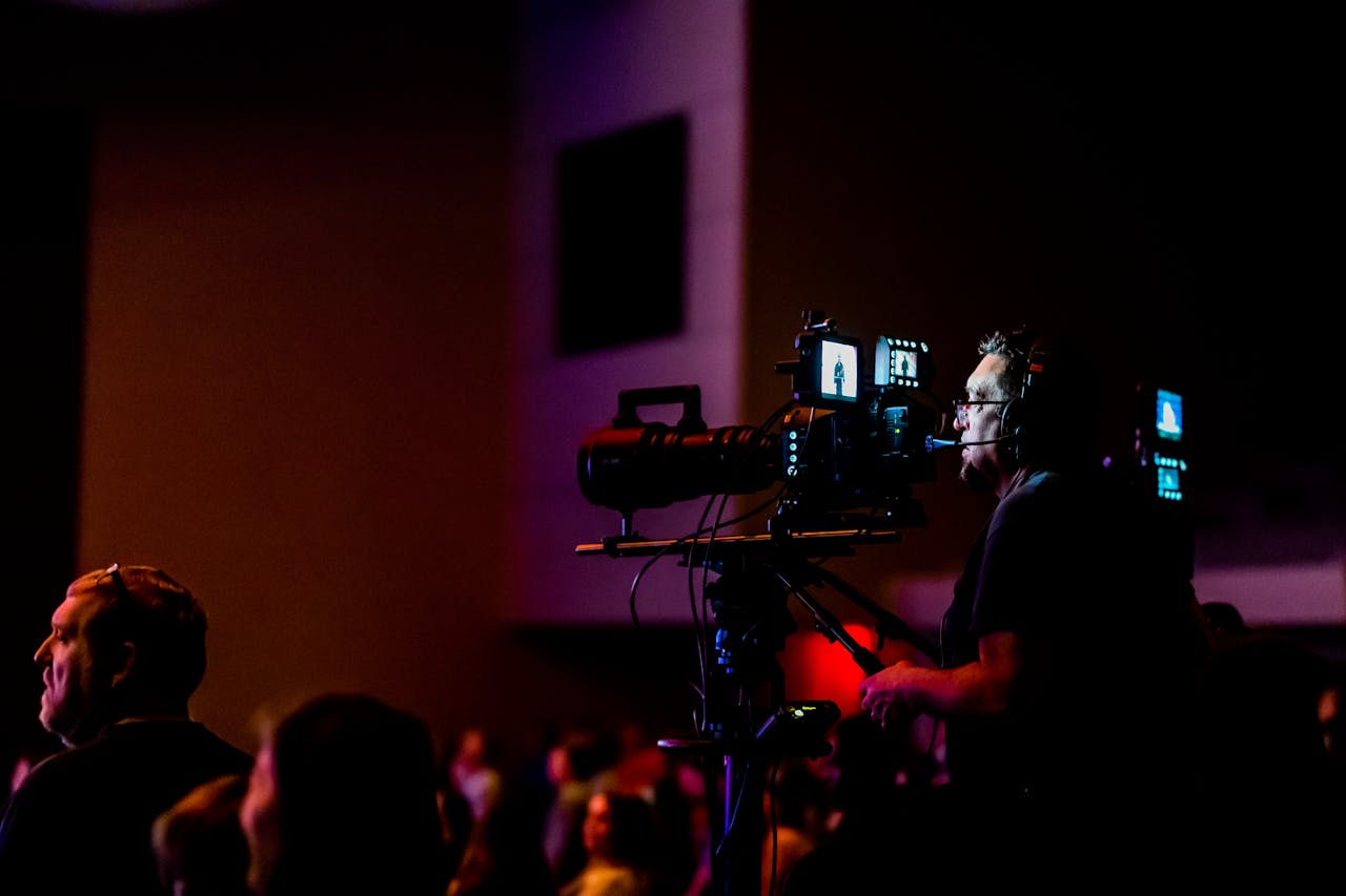 A videographer operates a camera during a live event, capturing the action professionally.