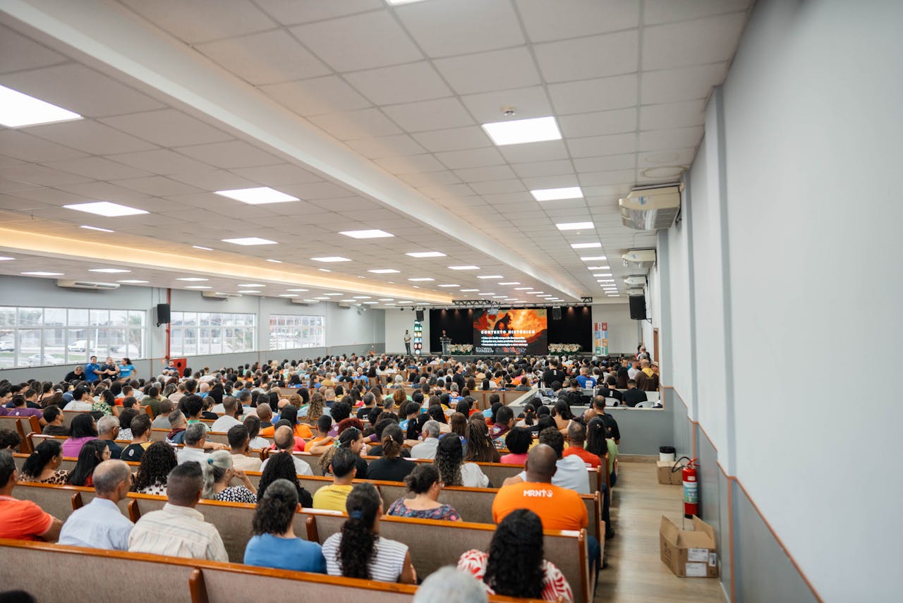 Large audience gathered in a spacious auditorium for a presentation or event with stage view.